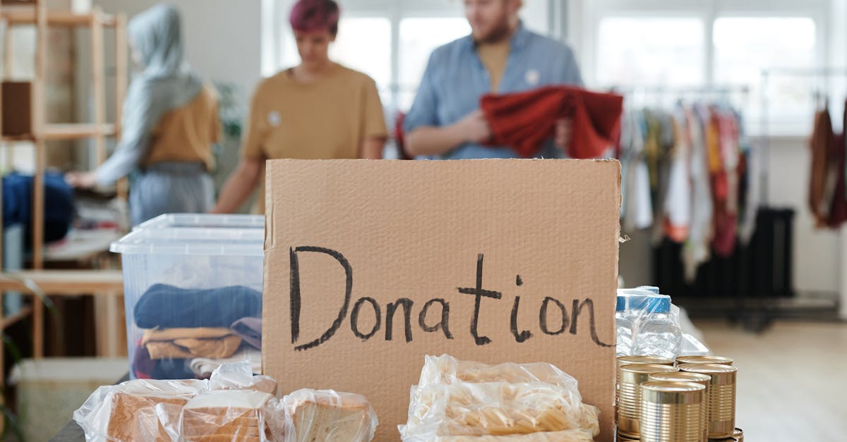 Volunteers sort clothes and food in a donation center. Cardboard sign reads 'Donation.'